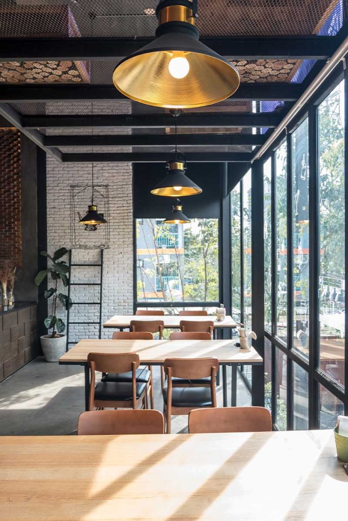 Close up of table and chair set in modern cafe minimalistic interior design with big window and hanging ceiling lamps